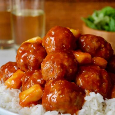 Baked Sweet and Sour Meatballs with pineapple on top of white rice in a white bowl
