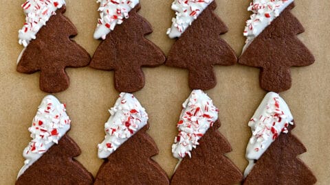 Chocolate sugar cookies in the shapes of Christmas trees dipped in white chocolate and sprinkled with crushed candy canes.
