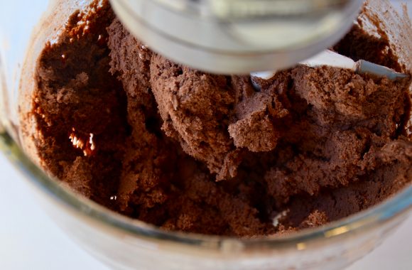 Chocolate sugar cookie dough in a glass stand mixer bowl with beater attachment