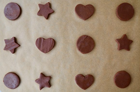 Cut-out circle, star and heart shapes made with chocolate sugar cookie dough