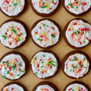 A top-down view of cutout Chocolate Sugar Cookies with frosting and rainbow sprinkles.