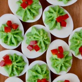 A wooden platter filled with Christmas Deviled Eggs