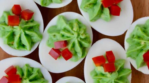 A wooden platter filled with Christmas Deviled Eggs
