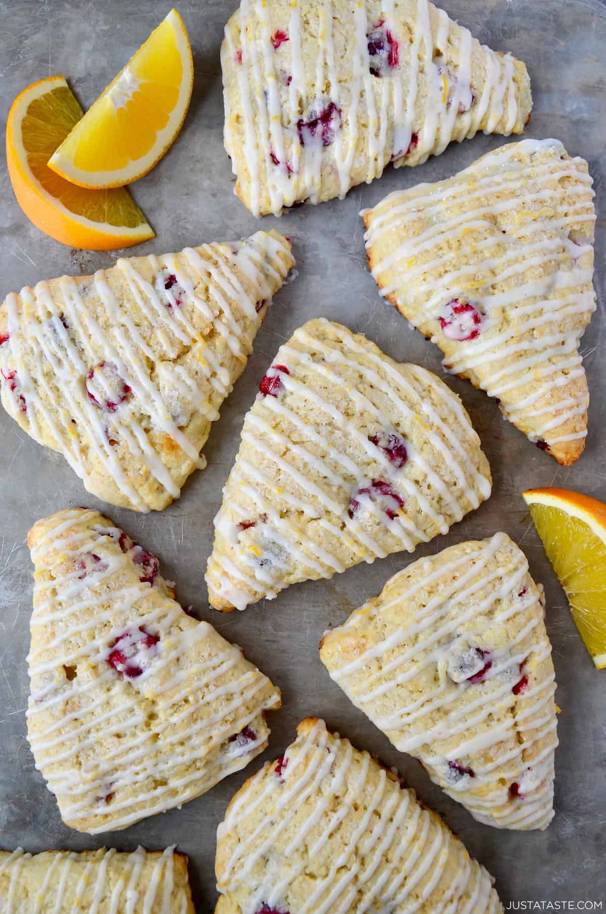 Cranberry orange scones with a simple orange glaze on a marble surface.