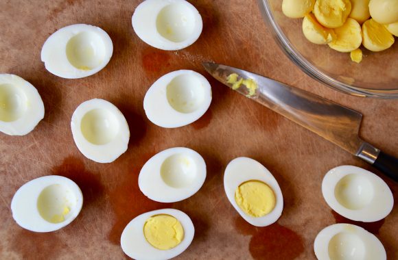 A wood cutting board with hardboiled eggs cut in half