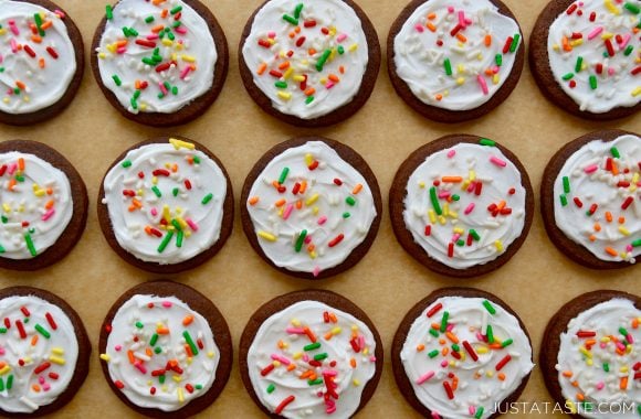 Rows of Chocolate Sugar Cookies topped with white frosting and rainbow sprinkles