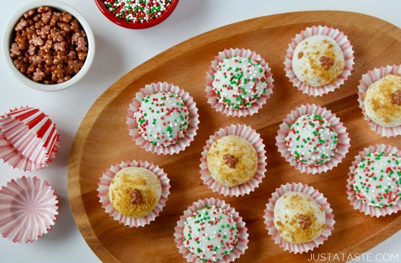 A wood plate with gingerbread cookie balls inside red and white paper cups