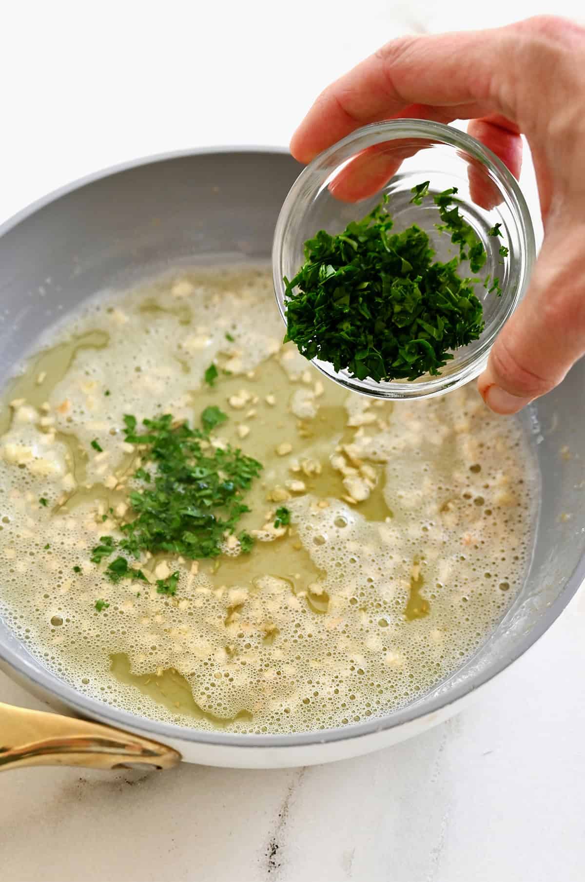 Adding chopped fresh parsley to the homemade garlic butter.