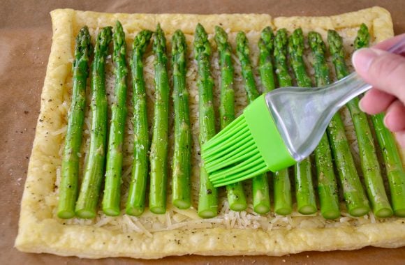 Cheesy Asparagus Tart being brushed with olive oil.
