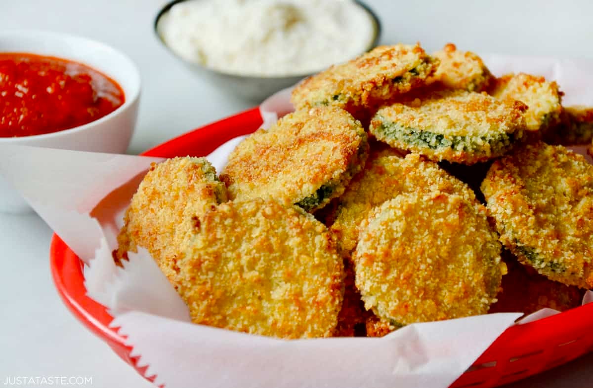 Golden brown and crispy baked zucchini chips in a red food basket lined with parchment paper.