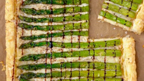 Cheesy Asparagus Tart drizzled with balsamic syrup on brown paper
