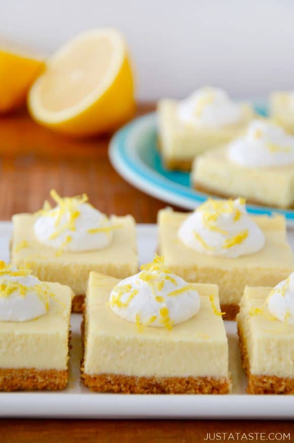 Easy Lemon Cheesecake Bars on white plate with cut lemon and more bars on a blue plate in background.