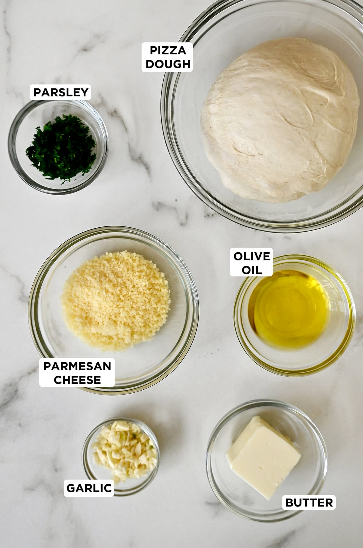 Ingredients to make garlic knots from pizza dough, brushed with garlic herb butter and sprinkled with Parmesan cheese.