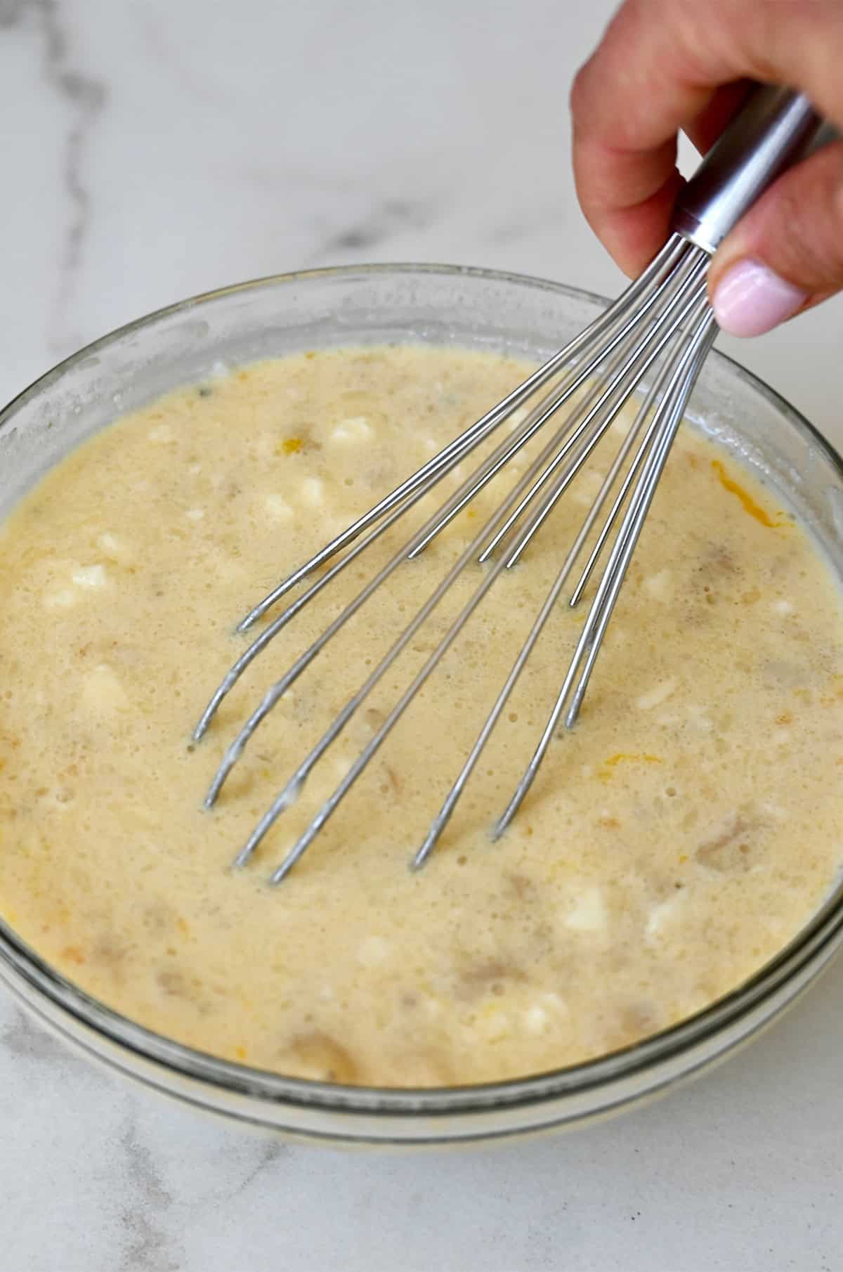 Wet ingredients for baked oatmeal being whisked together in a glass bowl.