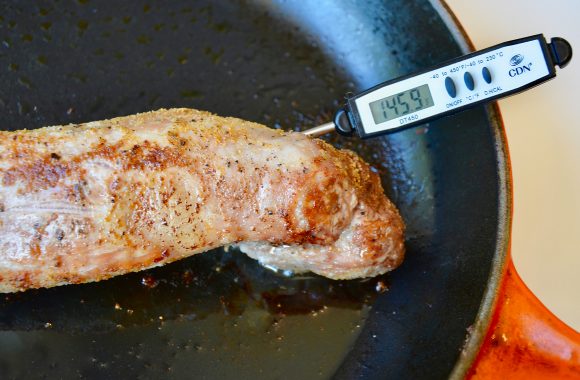 Pork tenderloin in skillet with thermometer reading 145.9 degrees fahrenheit. 