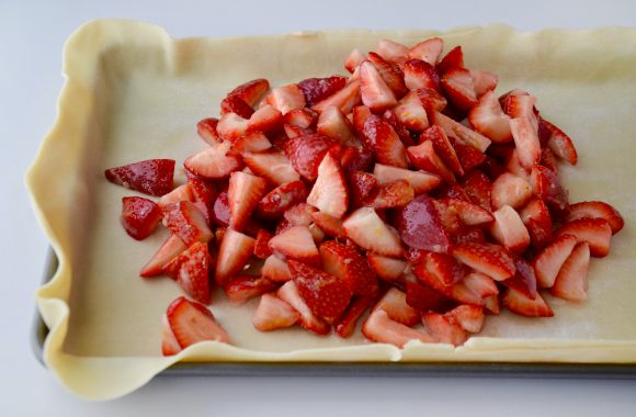Slab pie on baking sheet with strawberry mixture.
