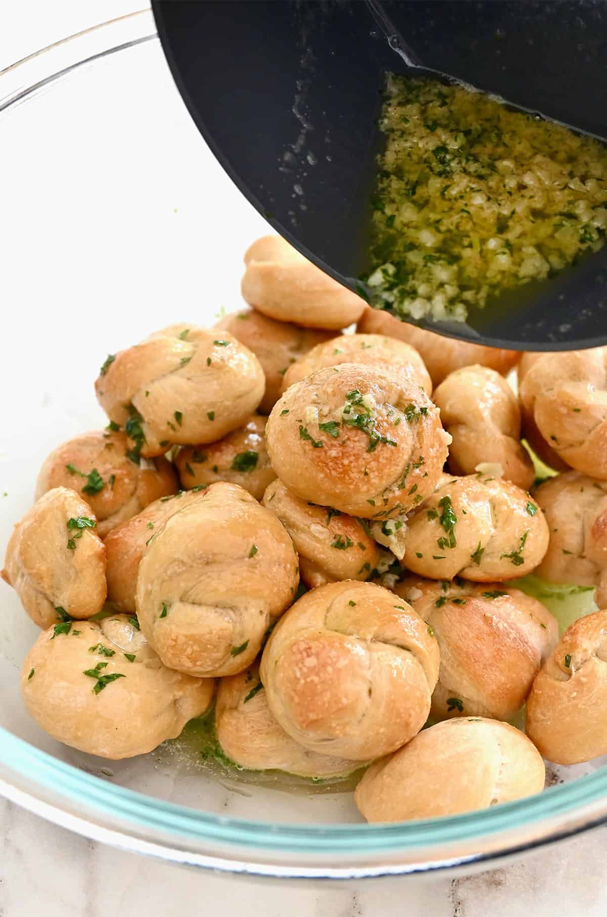 Tossing golden brown pizza knots with garlic herb butter.