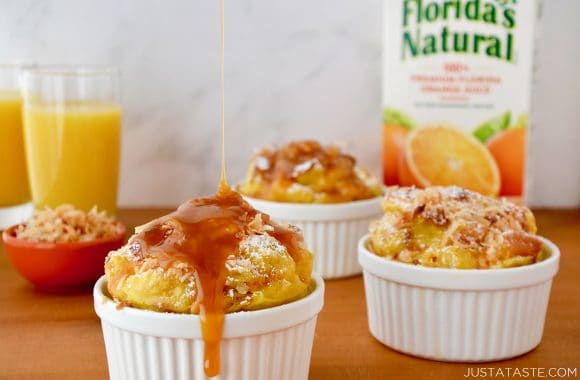 White ramekins filled with brioche bread pudding with orange juice in the background