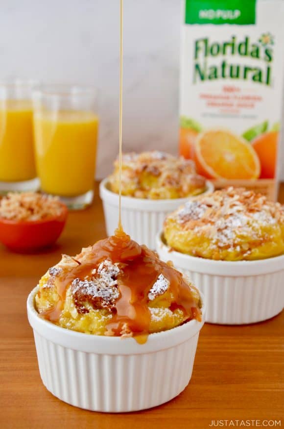 White ramekins filled with brioche bread pudding being drizzled with caramel sauce