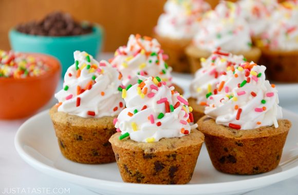A white plate containing Chocolate Chip Cookie Cups with bowls of sprinkles and chocolate chips in the background