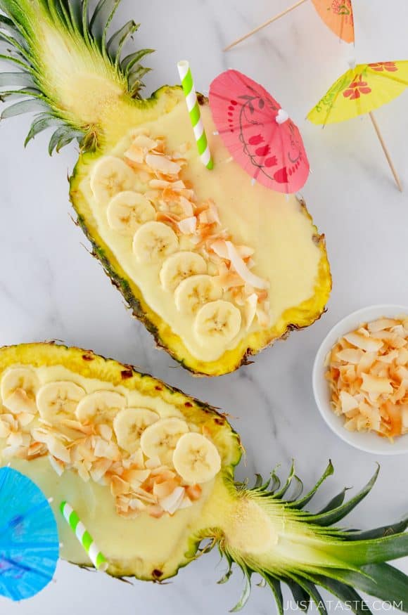 Pineapples hollowed out and filled with smoothie mixture topped with sliced bananas and coconut