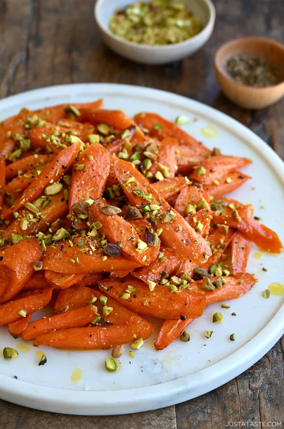 Caramelized honey roasted carrots garnished with crushed pistachios on a serving platter.