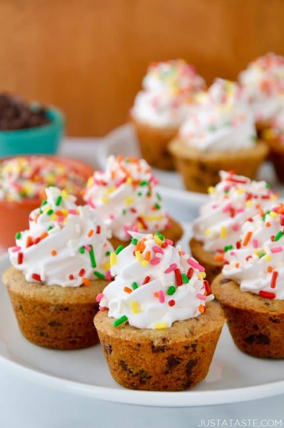 A white plate containing Chocolate Chip Cookie Cups topped with frosting and rainbow sprinkles
