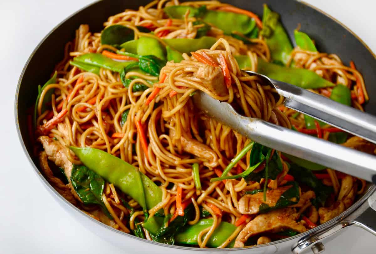 Easy Chicken Lo Mein in a skillet with tongs