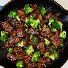 A large skillet containing beef and broccoli coated in a garlicky soy sauce.