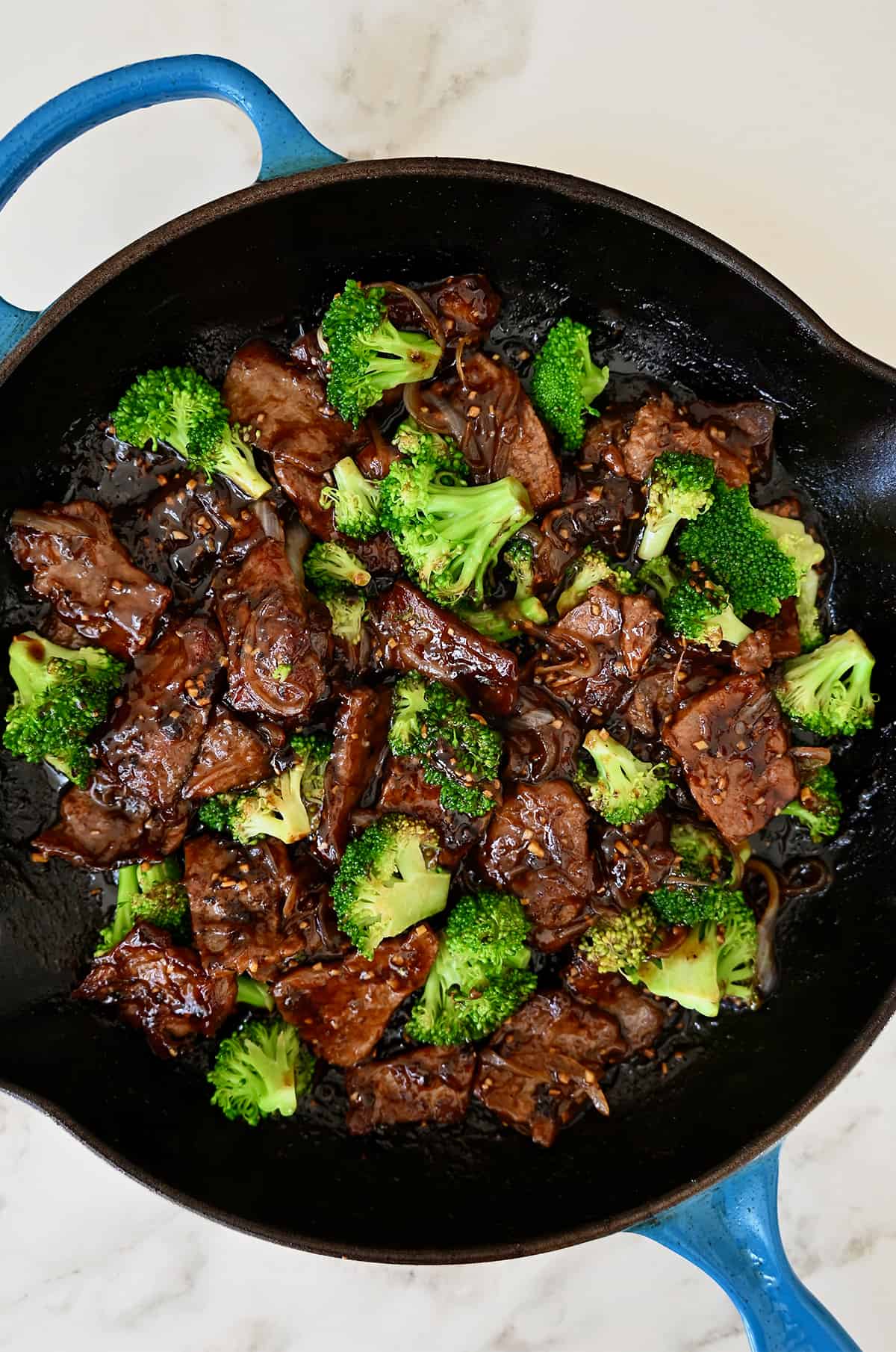 A large skillet containing beef and broccoli coated in a garlicky soy sauce.