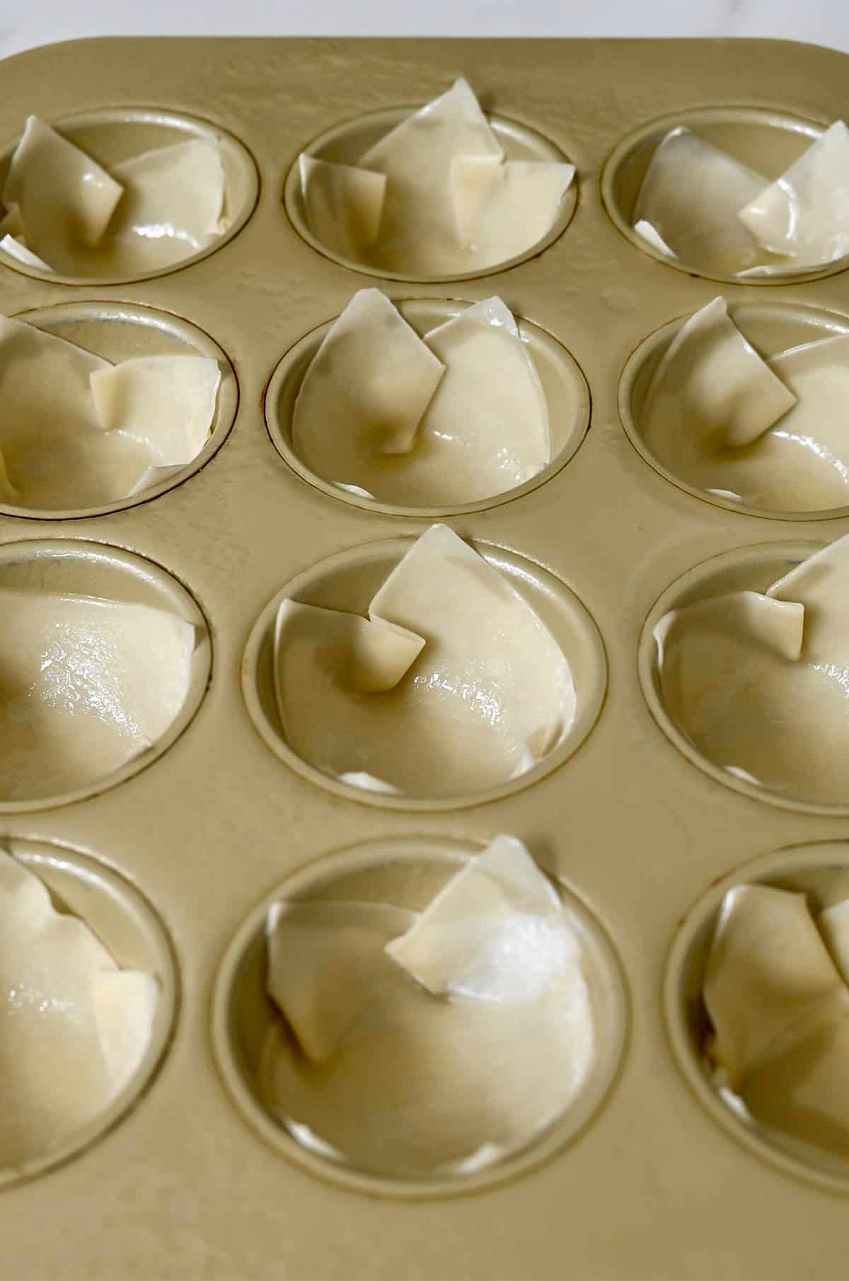 Wonton cups in a muffin tin sprayed lightly with cooking spray.