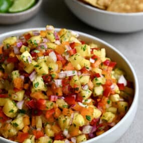 A white bowl containing pineapple salsa garnished with fresh cilantro.