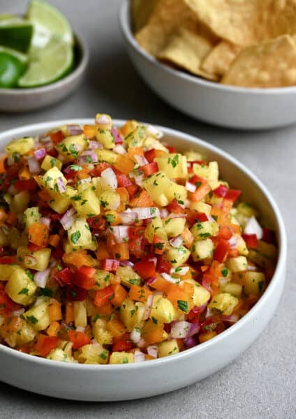 A white bowl containing pineapple salsa garnished with fresh cilantro.