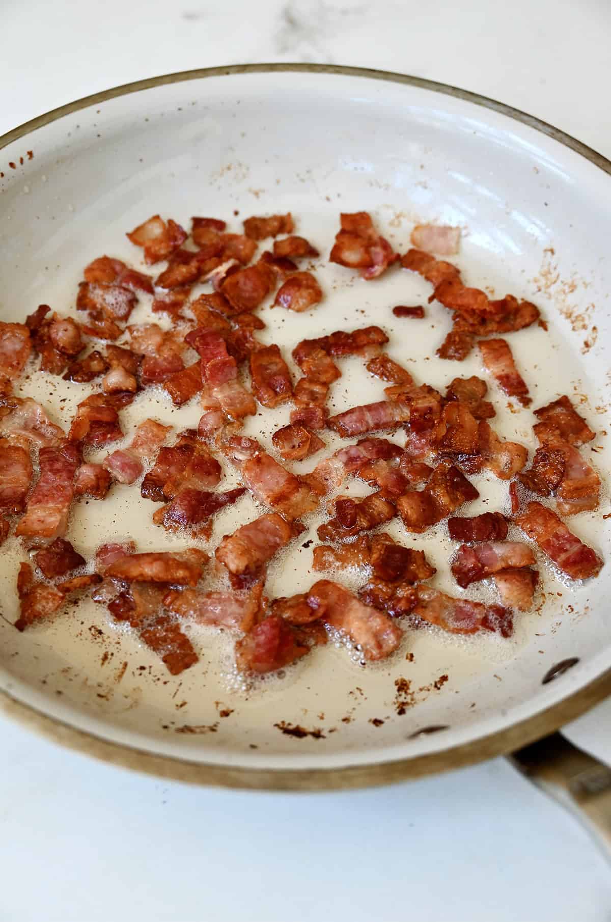 Cooked bacon pieces in a large skillet.