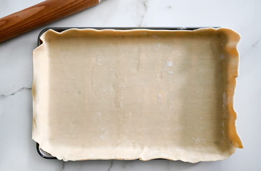 A baking sheet topped with pie dough next to a rolling pin