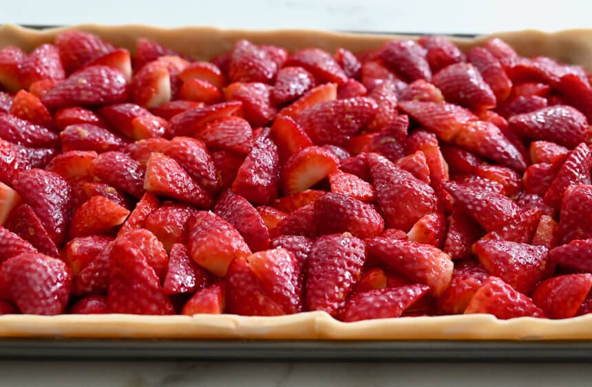 A close-up view of vibrant, sliced strawberries atop unbaked dough