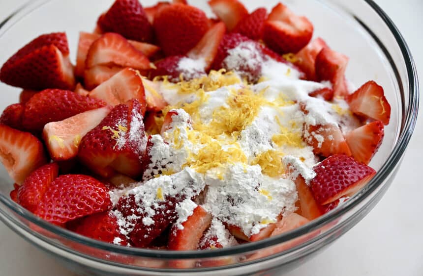 Sliced strawberries, cornstarch and lemon zest in a clear bowl