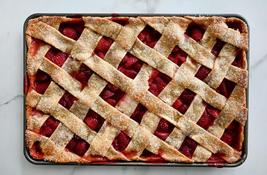 A top-down view of a lattice-topped strawberry slab pie