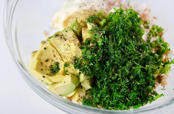 Large bowl containing chicken, avocado, mayonnaise, Dijon mustard, lime juice, sugar, scallions, dill and parsley