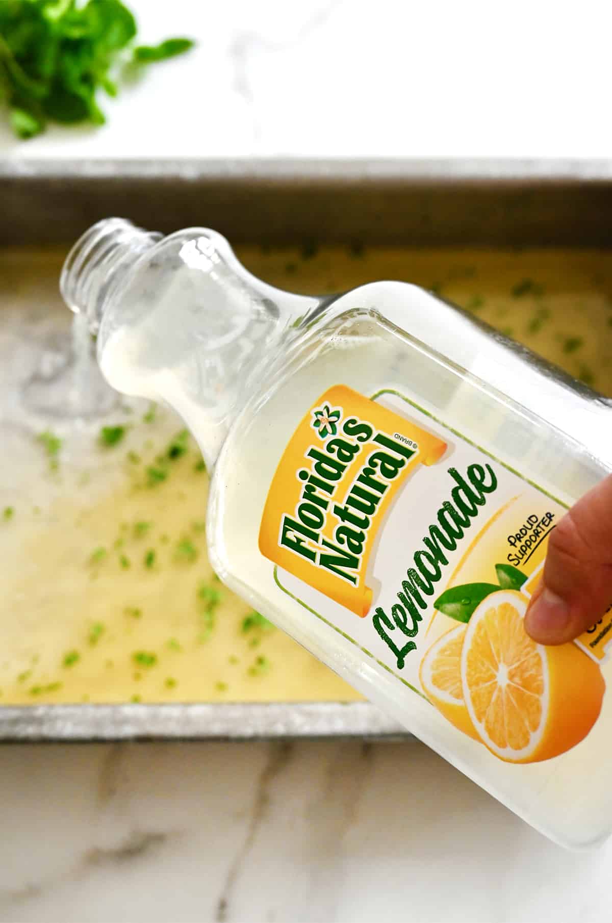 A hand holding a carton of Florida's Natural Lemonade over a baking sheet.