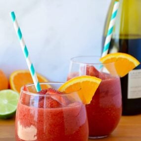 The Best Frozen Sangria with an orange slice and teal stripped straw