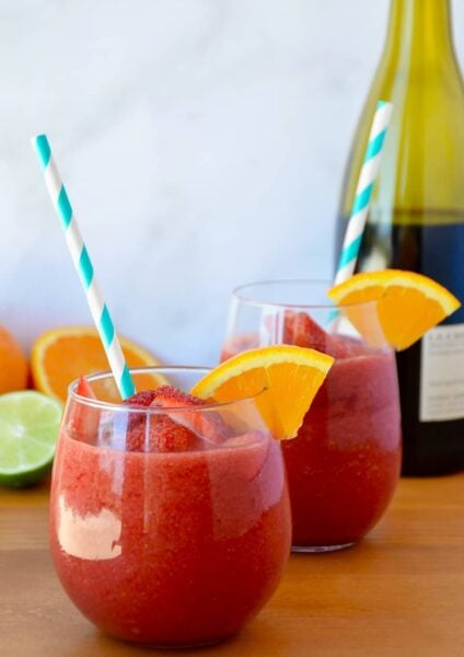 The Best Frozen Sangria with an orange slice and teal stripped straw