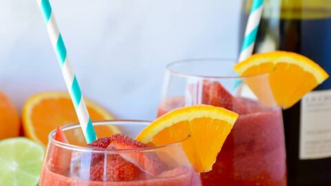 The Best Frozen Sangria with an orange slice and teal stripped straw
