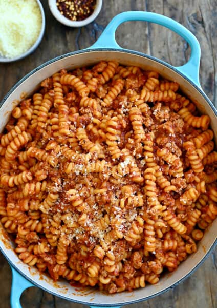 Pasta with marinara sauce and Italian sausage garnished with grated Parmesan cheese in a large stockpot.