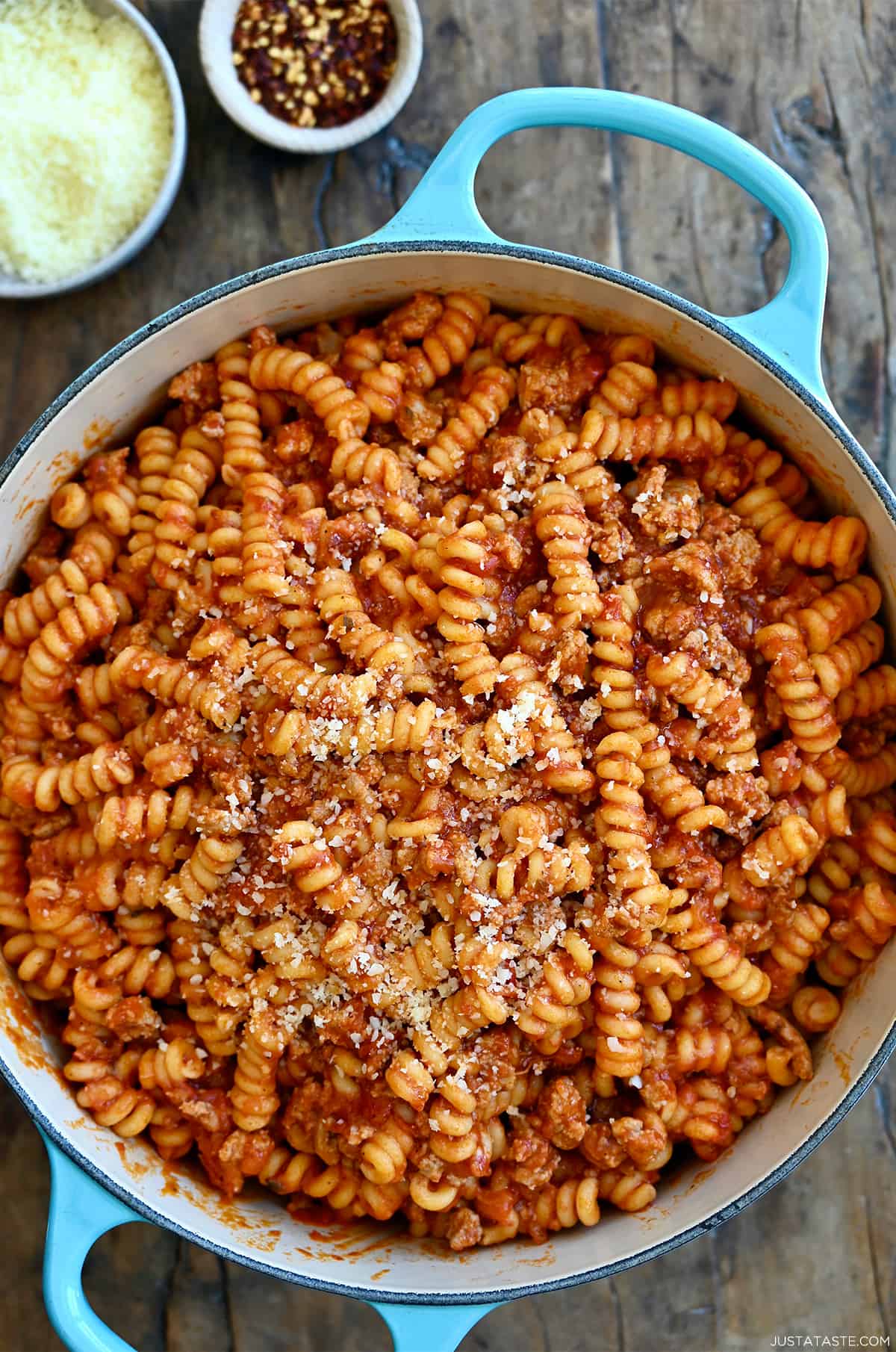 Pasta with marinara sauce and Italian sausage garnished with grated Parmesan cheese in a large stockpot.