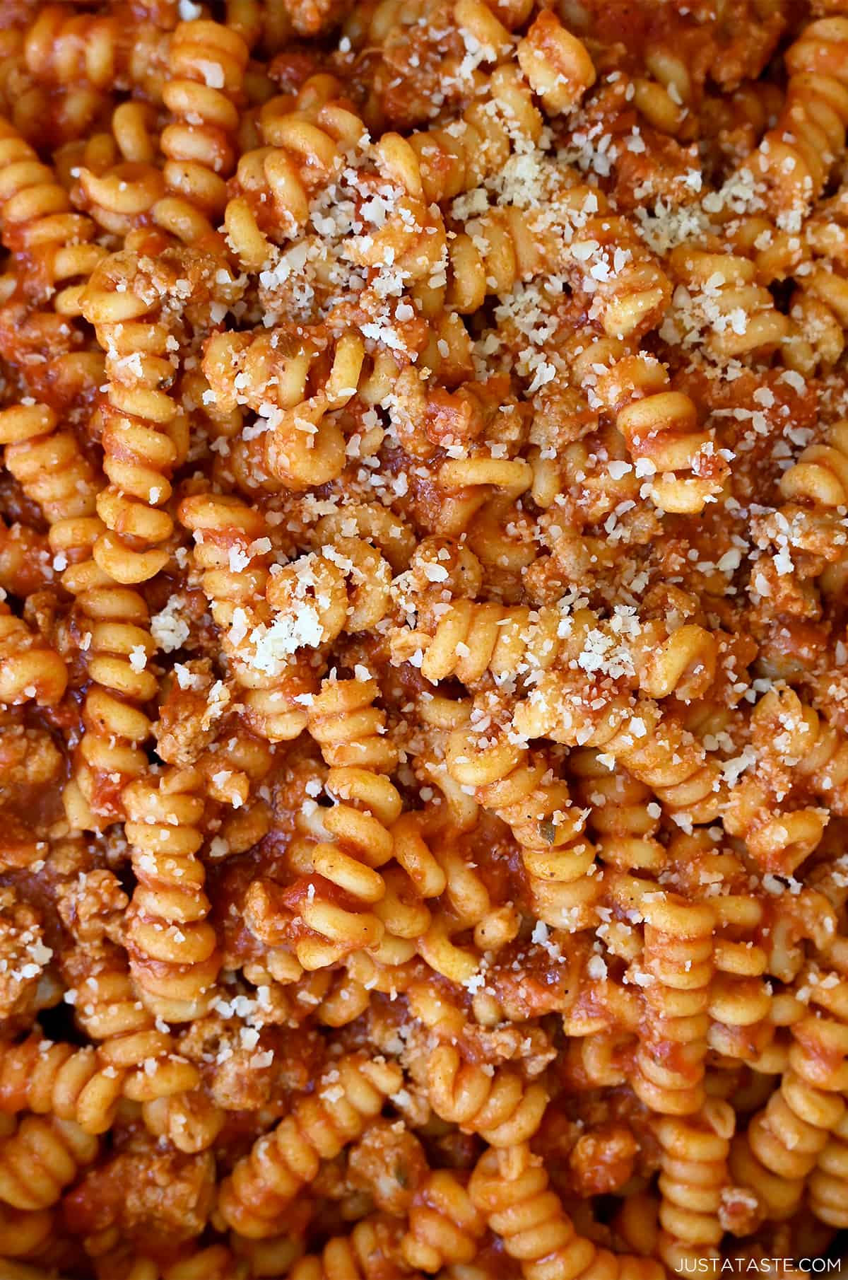 Spiral pasta covered in a hearty meat sauce and garnished with grated Parmesan cheese.