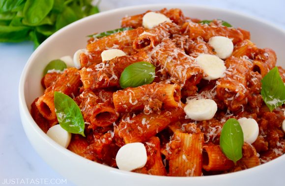 One Pot Pasta with Italian Sausage in white bowl with mozzarella, Parmesan and fresh basil