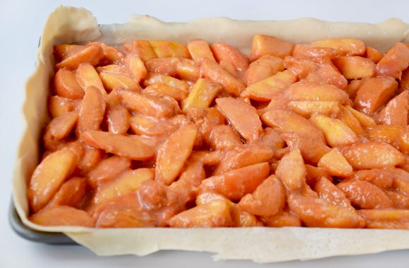 Baking sheet with pie crust and peach filling