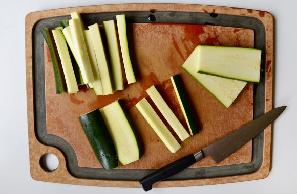 Cut zucchini on wooden cutting board with knife