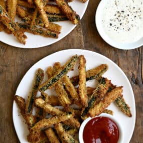 Crispy zucchini fries on a plate with a small bowl containing ketchup.